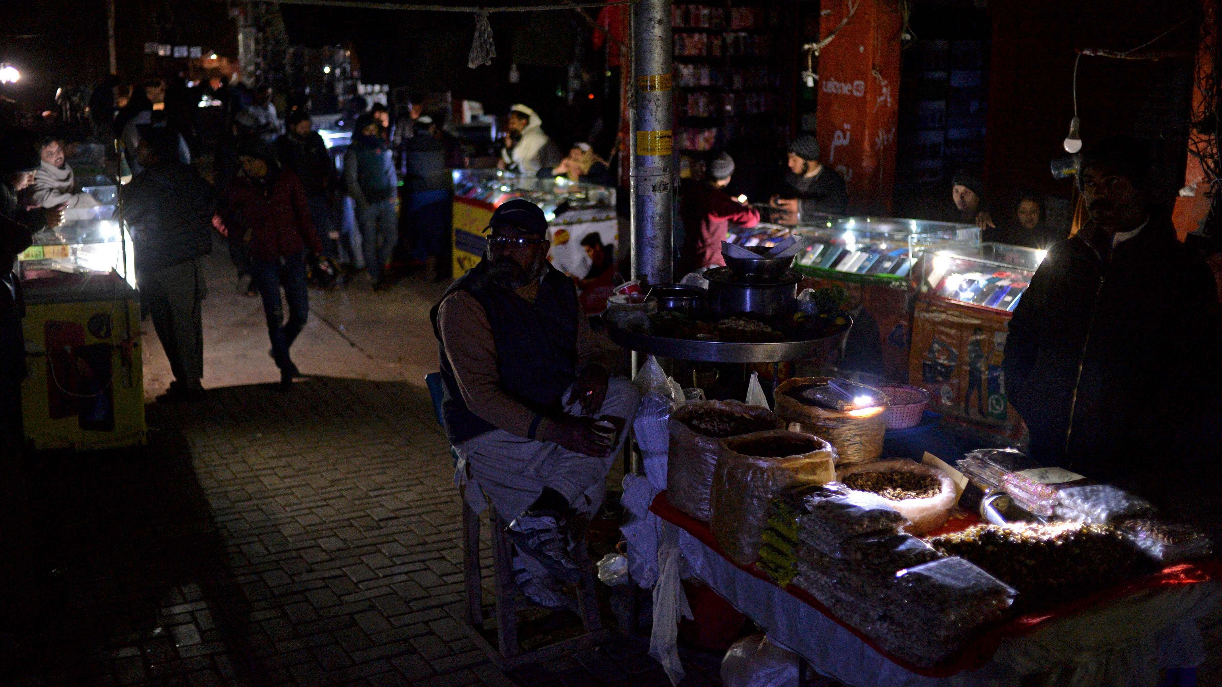 Shopkeepers sit at a market during a nationwide power outage, in Islamabad. Credit: AFP Photo