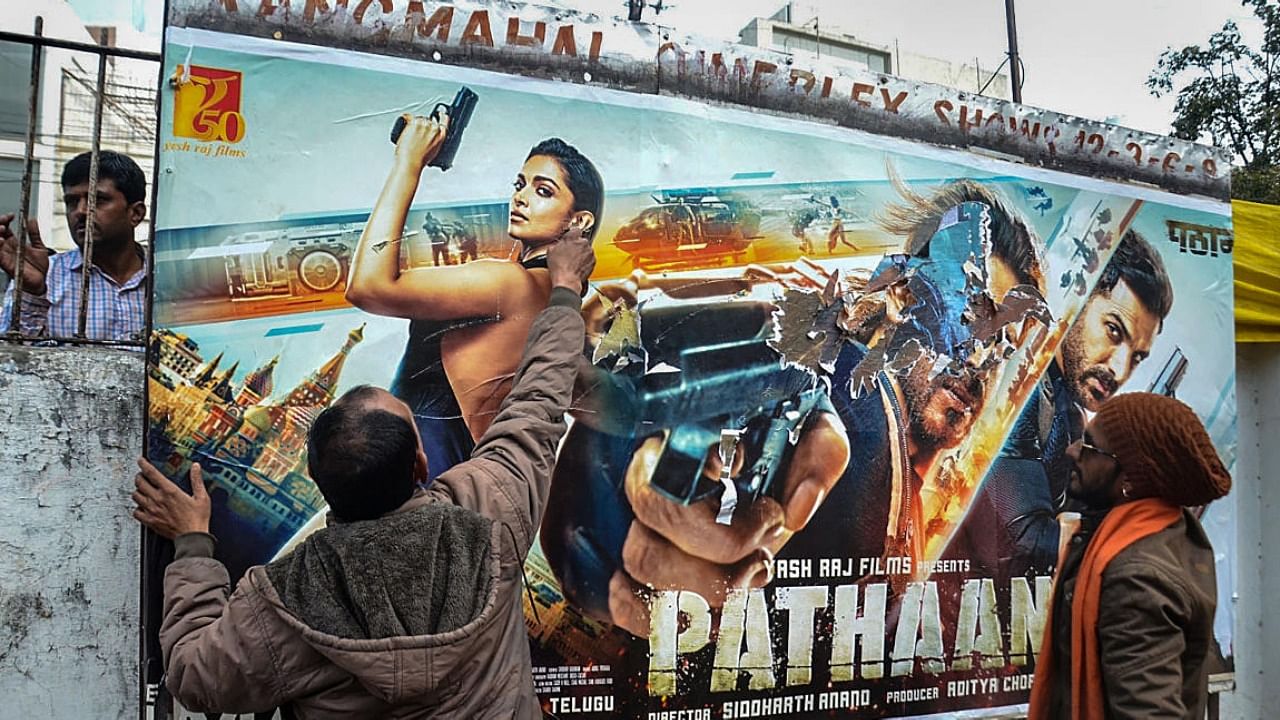 Members of Hindu Jagran Manch tear posters of the newly-released movie 'Pathaan' during a protest, in Bhopal. credit: PTI 