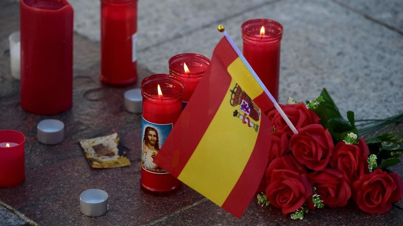 A picture taken on January 26, 2023 in Algeciras, southern Spain shows Spain's flag, flowers and candles displayed on the square near the church where a man was killed the day before. Credit: AFP Photo