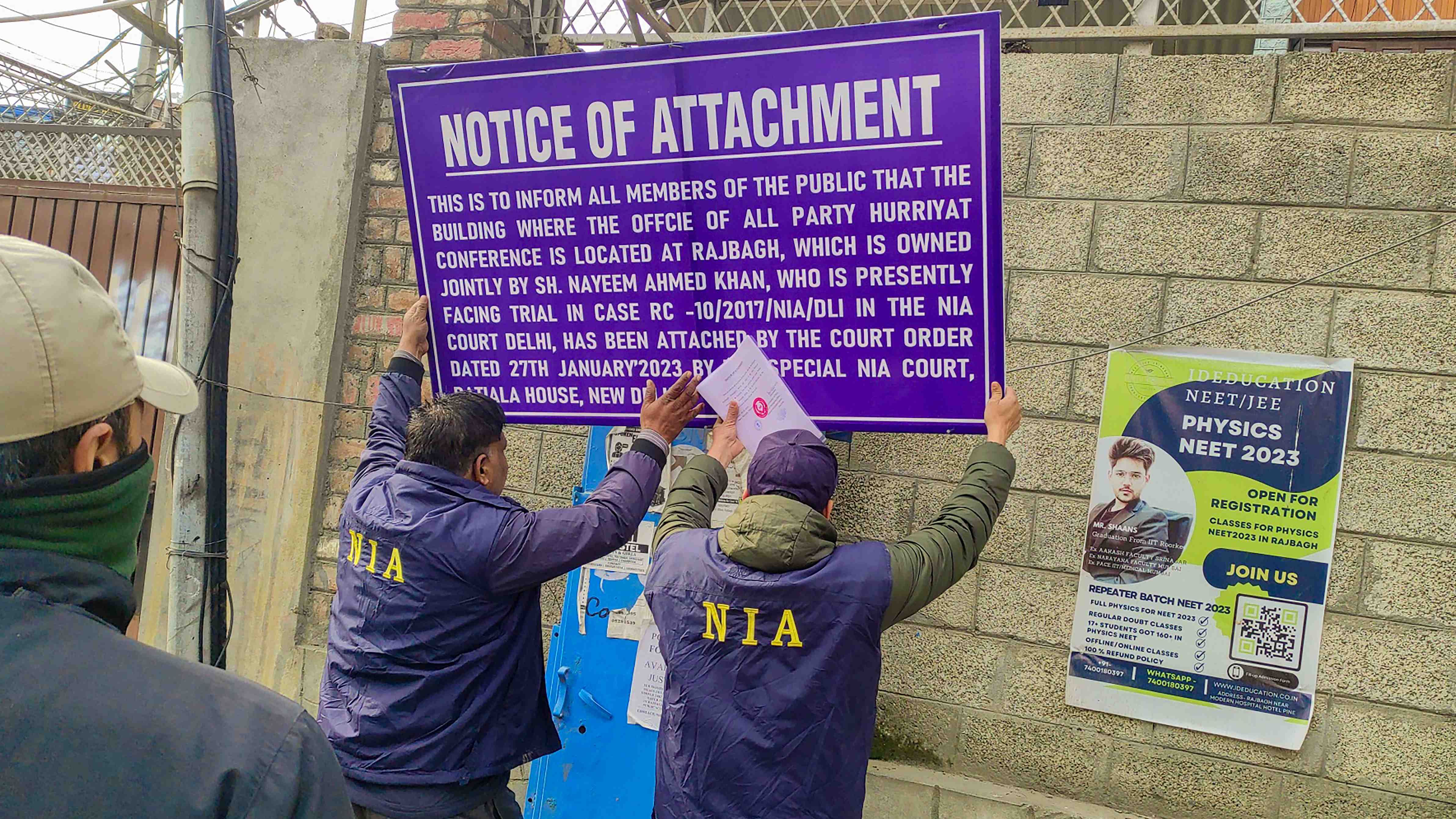  A National Investigation Agency (NIA) officers put up the Notice of Attachment board at the office of Hurriyat Conference in the Rajbhag area. Credit: PTI Photo