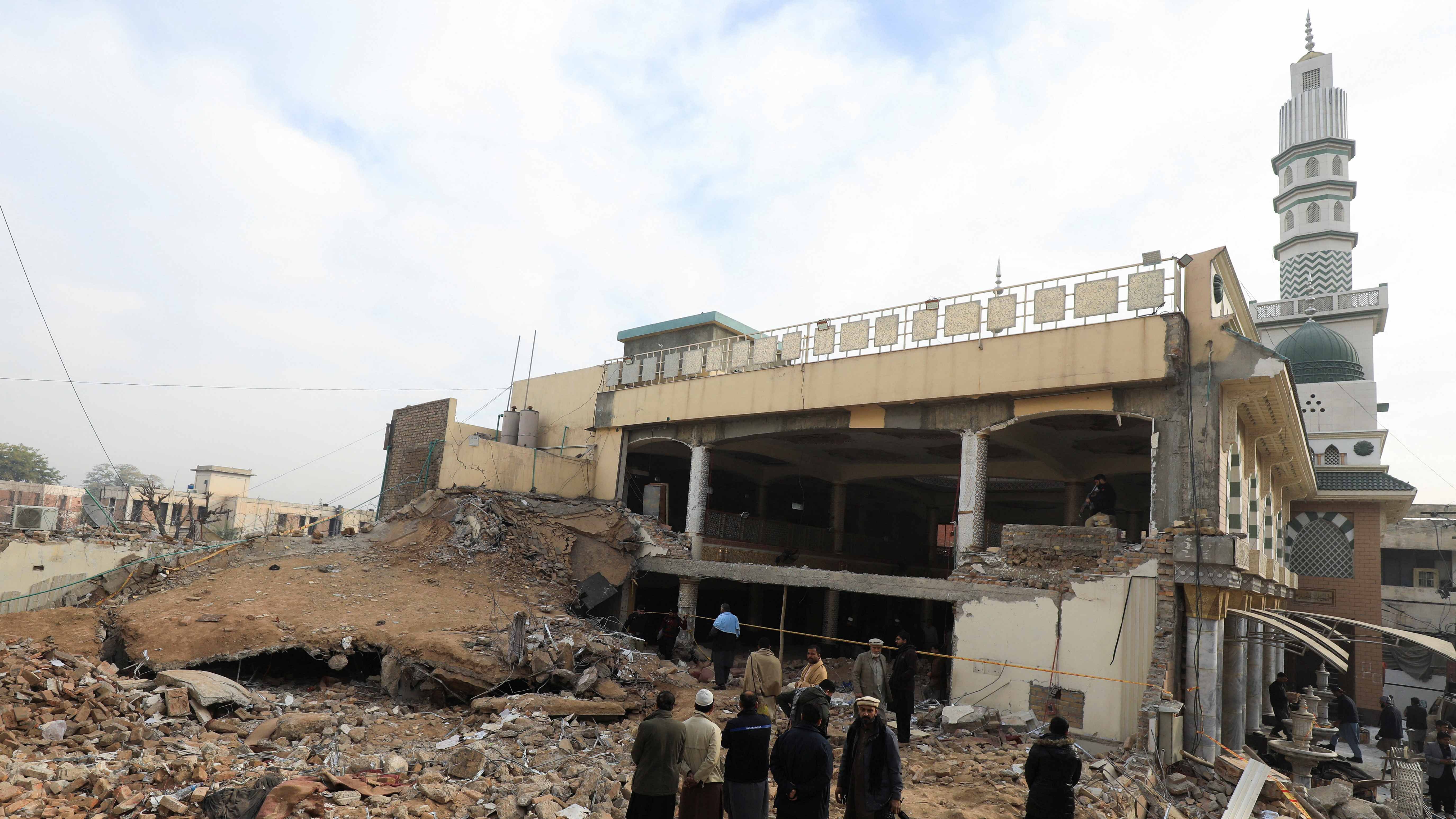 People stand amid the rubble, following a suicide blast in a mosque in Peshawar, Pakistan. Credit: Reuters Photo