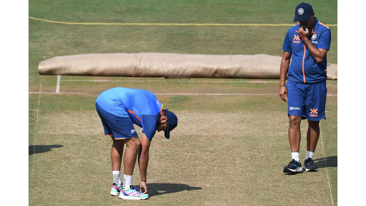 Skipper Rohit Sharma (left) feels the pitch as head coach Rahul Dravid watches on during a practice session in Nagpur on Tuesday. Credit: AFP