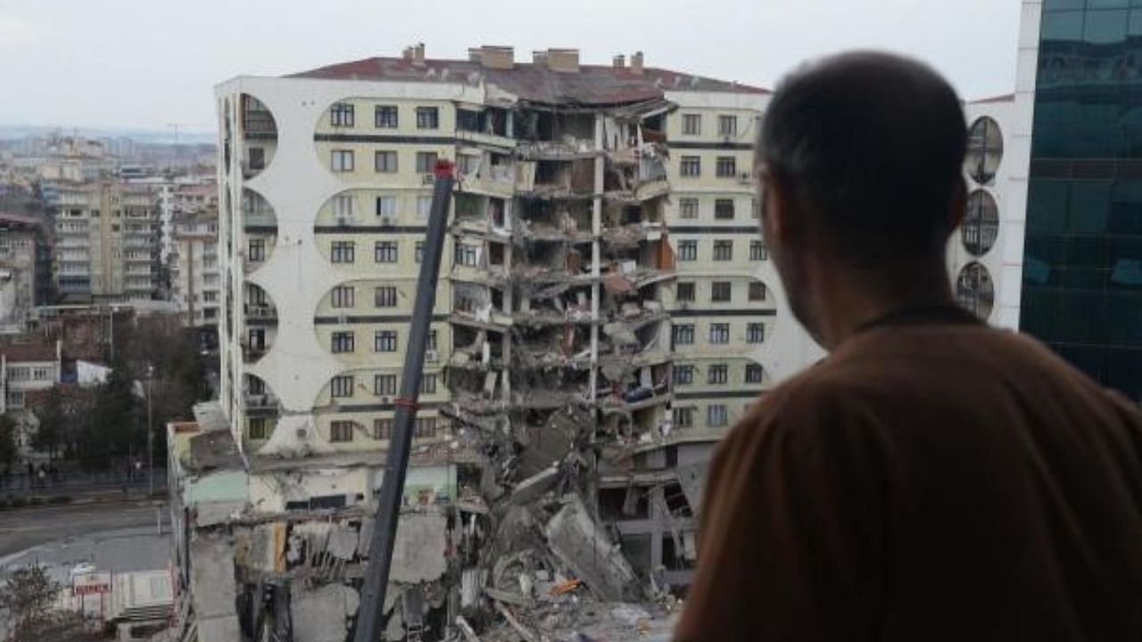  A man looks on at search and rescue operations conducted in the rubble of a collasped building, in Turkey. Credit: AFP Photo