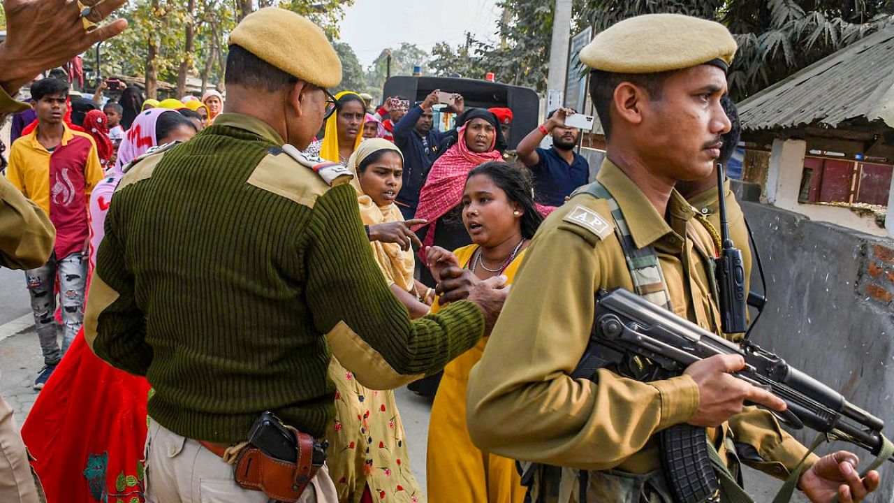 A policeman speaks with relatives of people arrested by police for their alleged involvement in child marriages, during Assam government's statewide crackdown on child marriages, outside Mayong police station in Morigaon district. Credit: PTI Photo