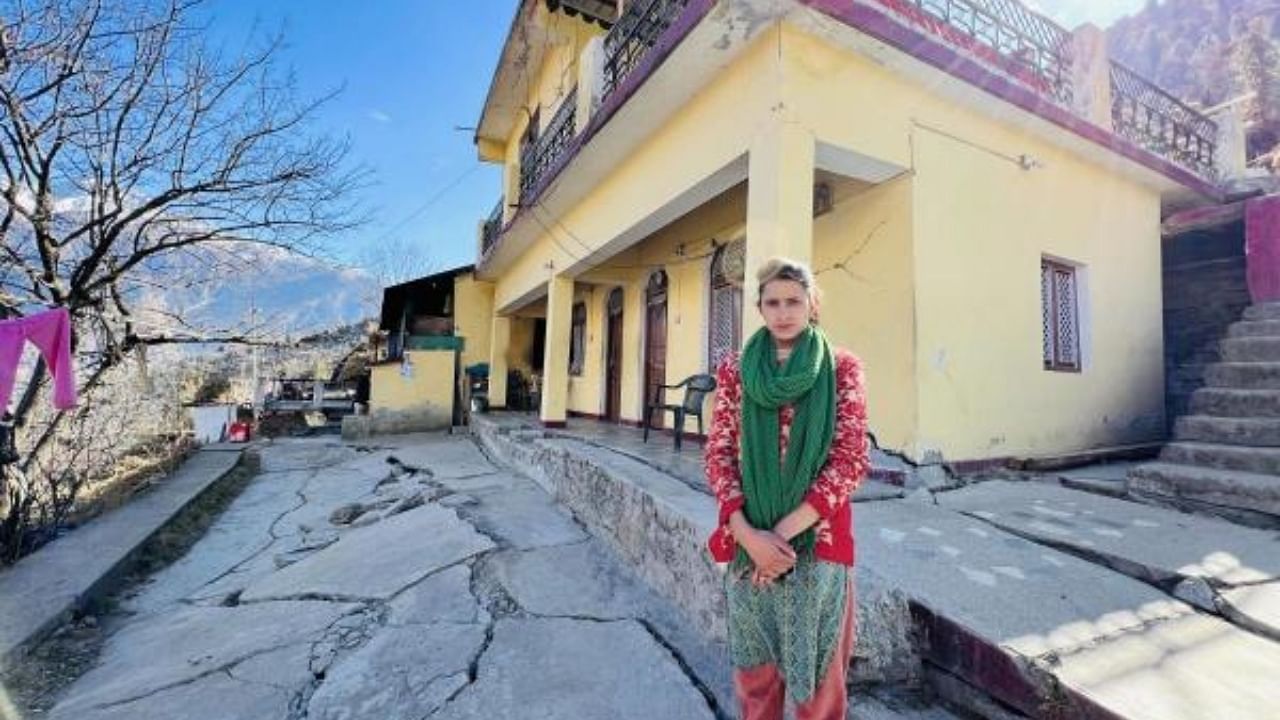 Joshimath resident Neha Saklani near her land subsidence hit house. Credit: PTI Photo