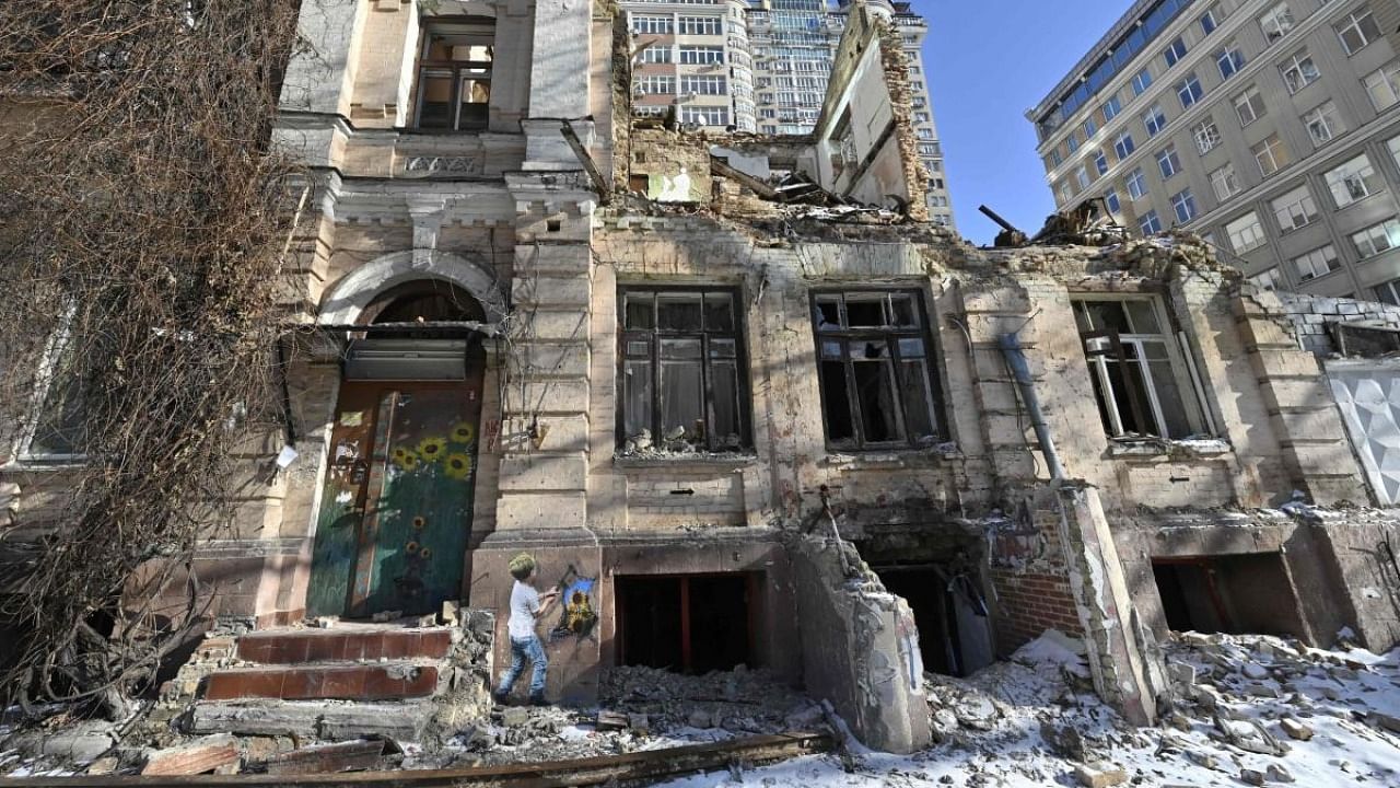 A photograph taken on February 8, 2023 shows a mural by Italian urban artist Tvboy on the wall of a destroyed residential building in Kyiv, during the Russian invasion of Ukraine. Credit: AFP Photo