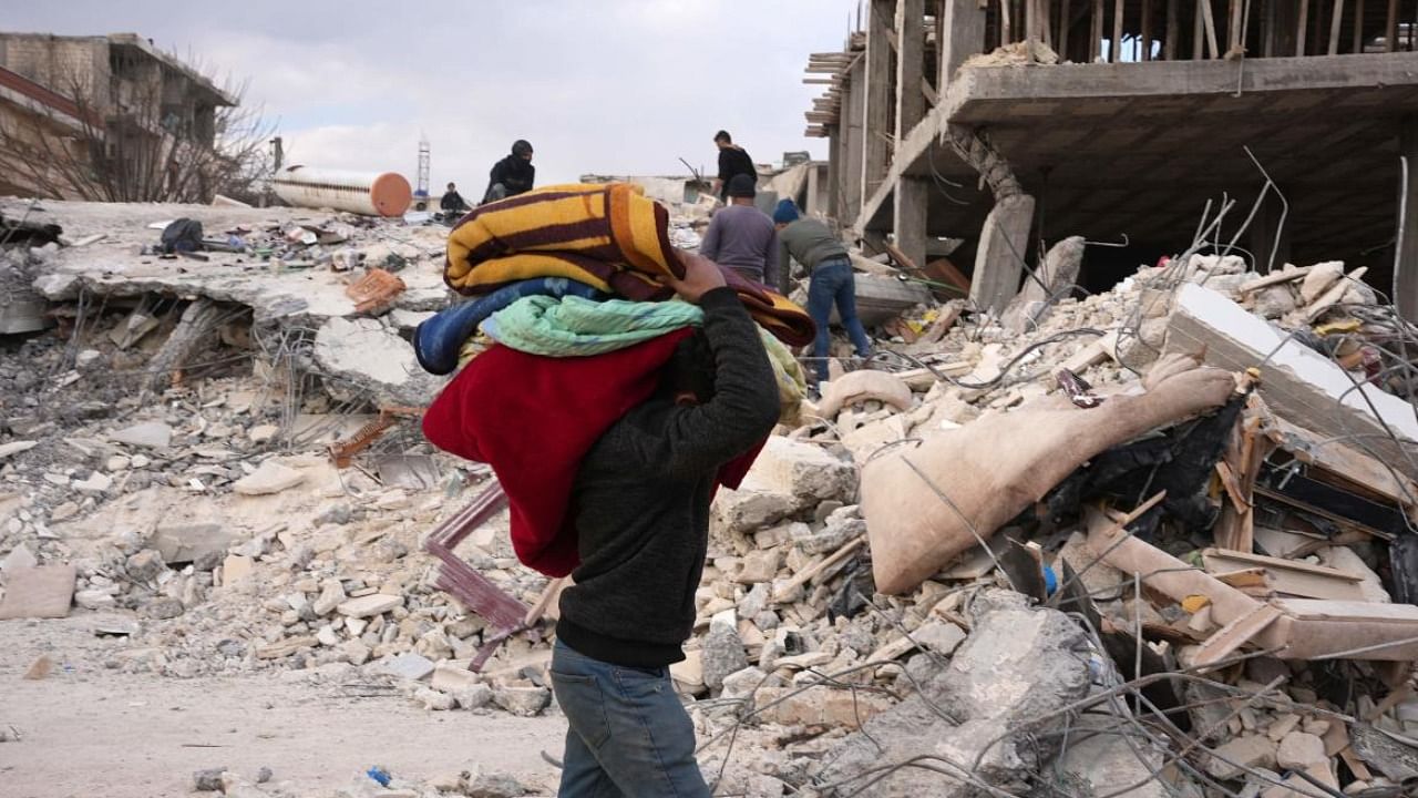 Residents salvage some blankets amid ongoing search and rescue operations continue days after a deadly earthquake hit Turkey and Syria, in the town of Jindayris. Credit: AFP Photo