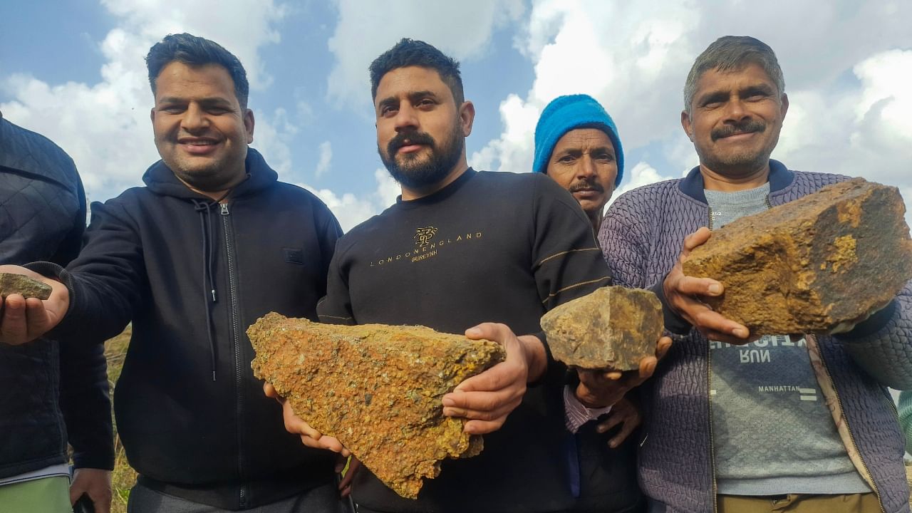 Residents of Salal village pose for photos showing lithium stones, in Reasi district, Saturday, Feb. 11, 2023. Credit; PTI Photo