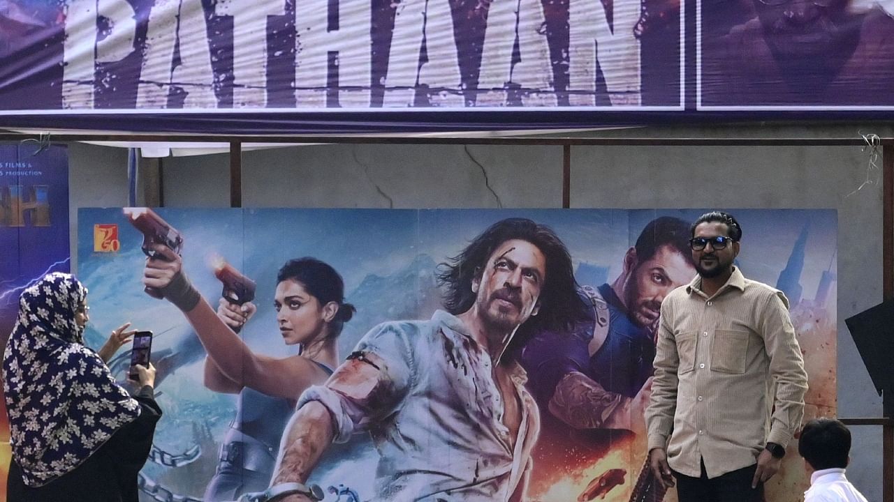 Moviegoers pose for pictures in front of a poster of the Bollywood movie 'Pathaan' outside a cinema hall in Prayagraj on January 25, 2023. Credit: AFP File Photo