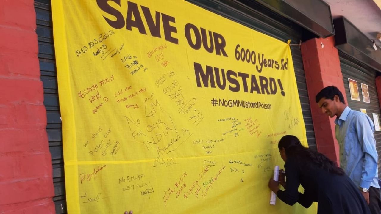 People sign a cloth banner with messages as part of the awareness programme in Bengaluru on Sunday. Credit: India for Safe Food