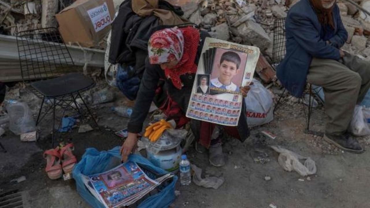 A woman holds pictures of her missing grandchildren in Hatay, Turkey on February 12, 2023. Credit: AFP Photo
