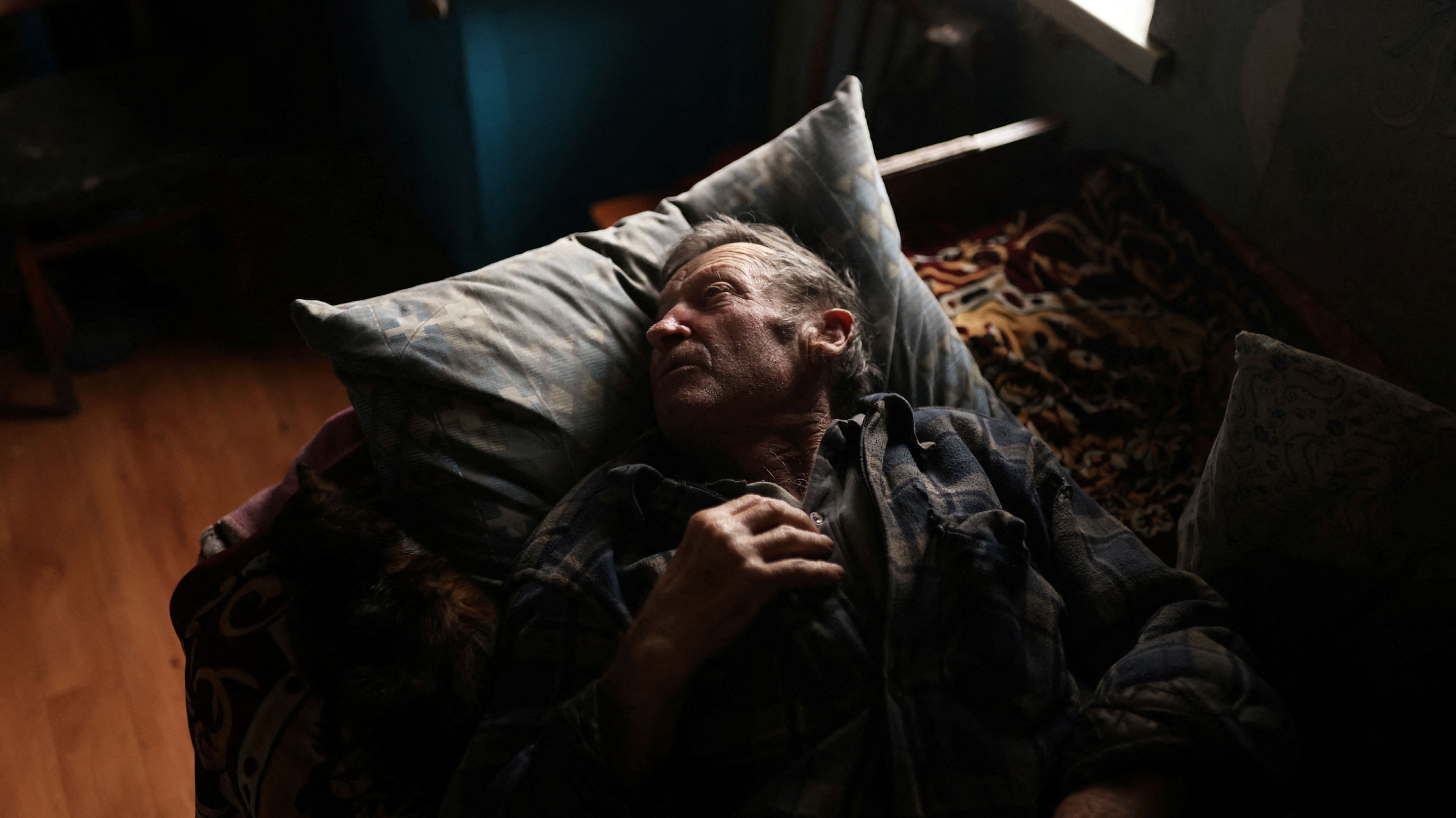 Volodymyr Kovalyov, 77, who remained in his village throughout the conflict and was in his house in October when it was hit by what he thinks was a tank shell, lays in a bed in the last room of his house. Credit: Reuters Photo