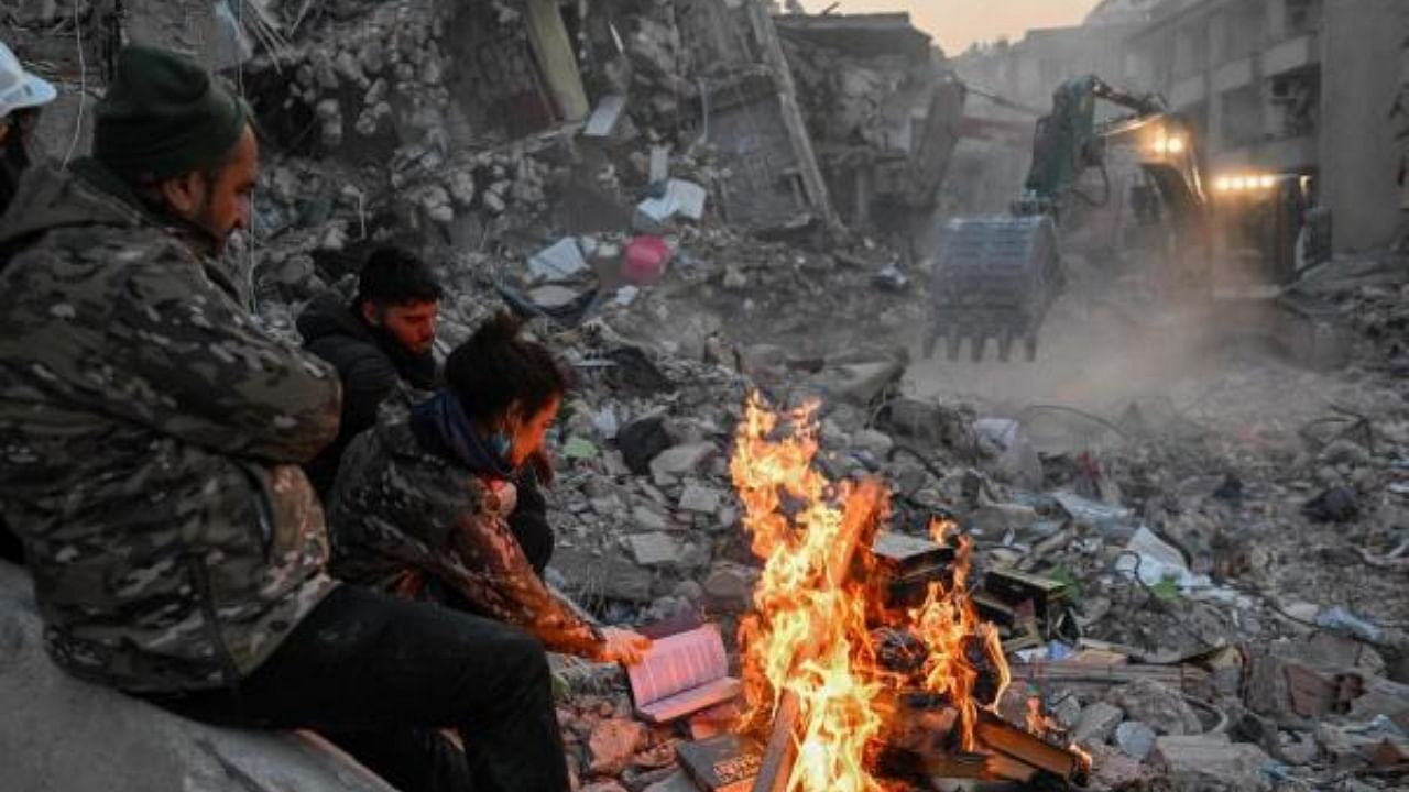 Local residents burn books to keep warm as they wait for their relatives to be pulled out from the rubble of collapsed buildings in Hatay, Turkey, on February 14, 2023. Credit: AFP Photo