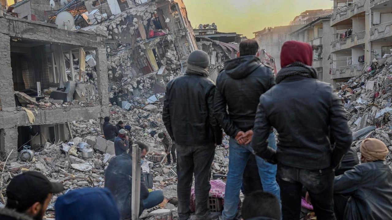  Local residents look at the collapsed buildings in Antakya Credit: AFP Photo