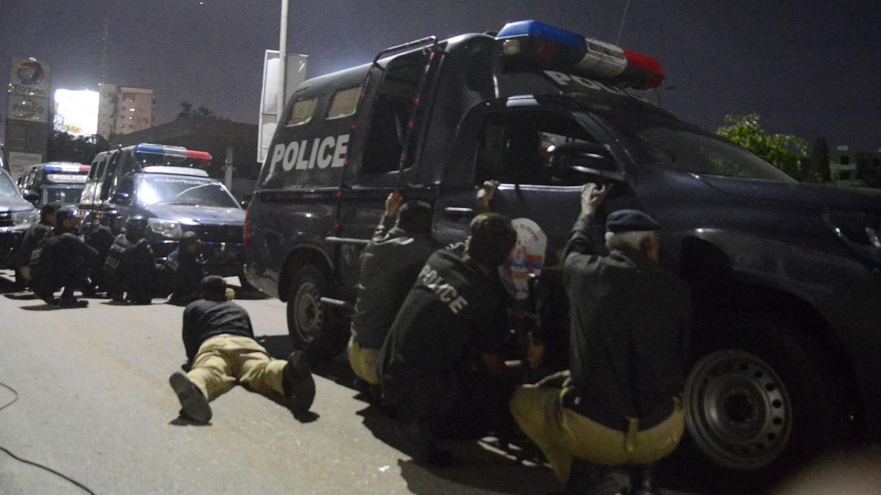 Policemen take position near the site of an attack to a police compound in Karachi. Credit: AFP Photo