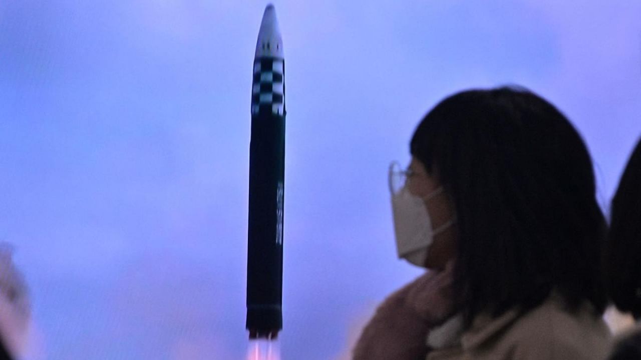 A woman walks past a television showing a news broadcast with file footage of a North Korean missile test. Credit: AFP Photo