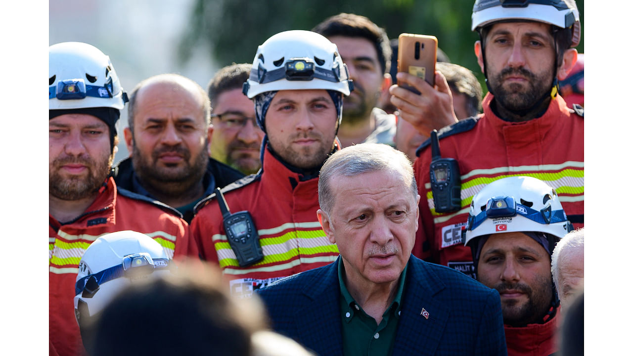 Turkish President Recep Tayyip Erdogan stands with rescue workers as he visits the hard-hit southeastern province of Hatay. Credit: AFP Photo