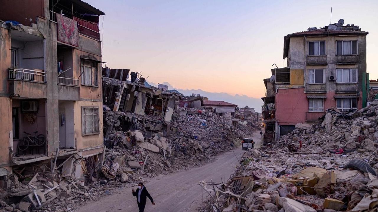 A man walks past collapsed buildings in Antakya, southern Turkey. credit: AFP