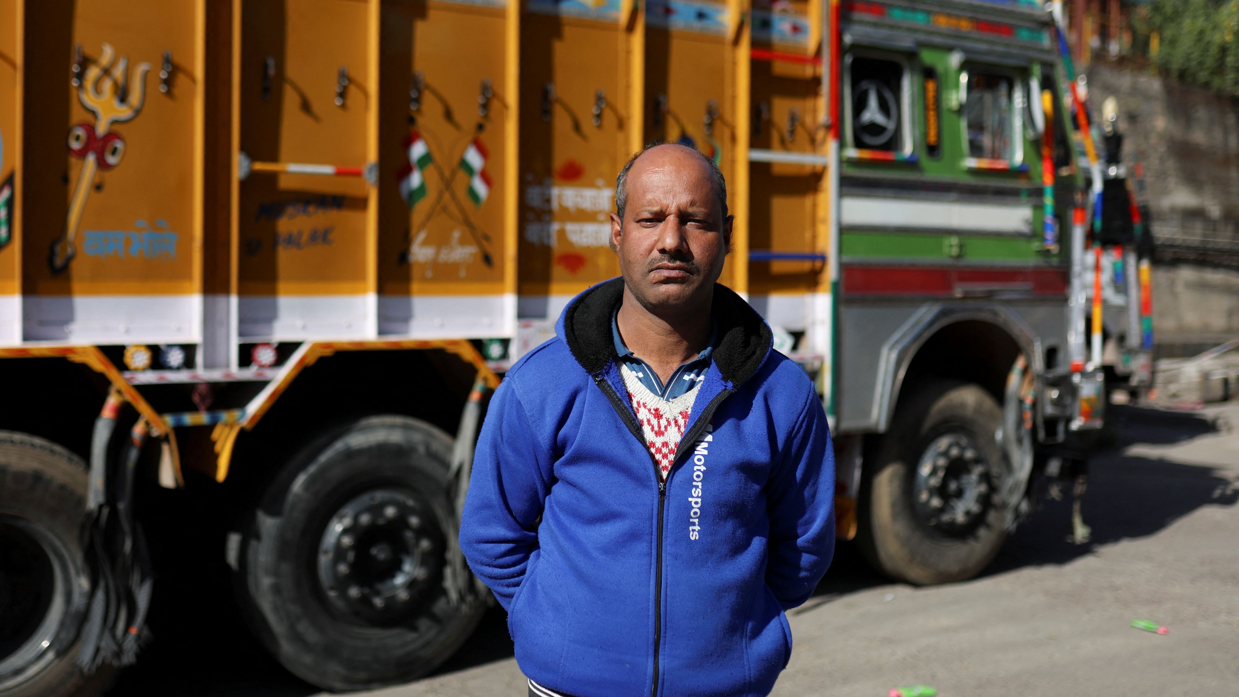 Lokram, a truck owner, poses for a picture near parked trucks next to the Ambuja Cements Limited plant owned by Adani Group in Darlaghat, Solan district in the state of Himachal Pradesh, India. Credit: Reuters Photo