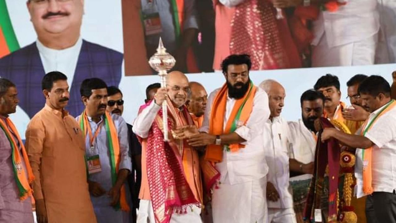 Union Home Minister Amit Shah is presented with a mace during the party’s public rally in Sandur of Ballari district on Thursday. State BJP president Nalin Kumar Kateel, Minister B Sriramulu and senior leader B S Yediyurappa are seen. Credit: DH Photo