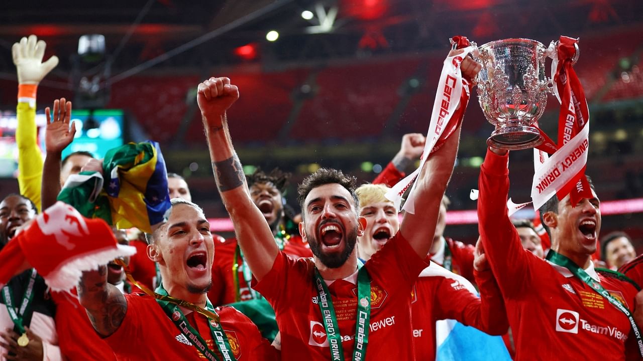 Manchester United's Antony and Bruno Fernandes celebrate with the trophy after winning the Carabao Cup. Credit: Reuters Photo