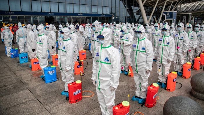 Staff members line up at attention as they prepare to spray disinfectant at Wuhan Railway Station in Wuhan in China's central Hubei province on March 24, 2020. Credit: AFP File Photo