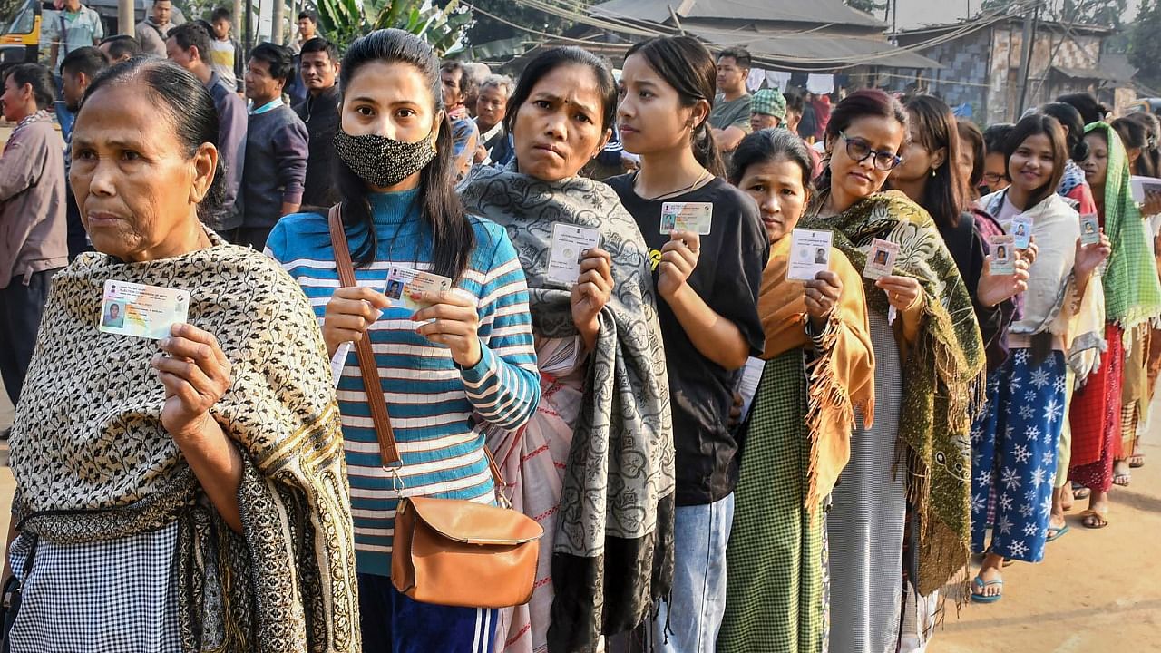 Voters show their identification cards as they wait in a queue to cast their votes at a polling booth during the Meghalaya Assembly elections. Credit: PTI Photo