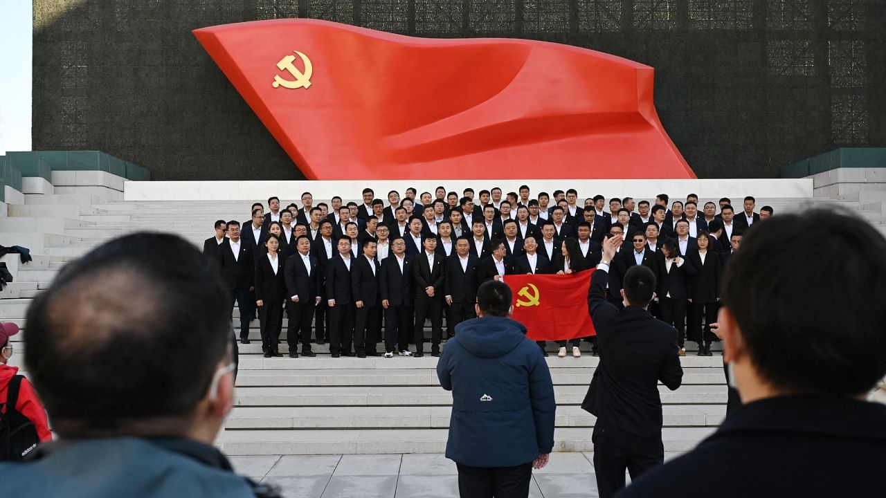 People pose for photos in front of the Chinese Communist Party flag during a visit to the Museum of the Communist Party of China in Beijing on March 3, 2023, ahead of the opening of the annual session of the National People’s Congress on March 5. Credit: AFP Photo