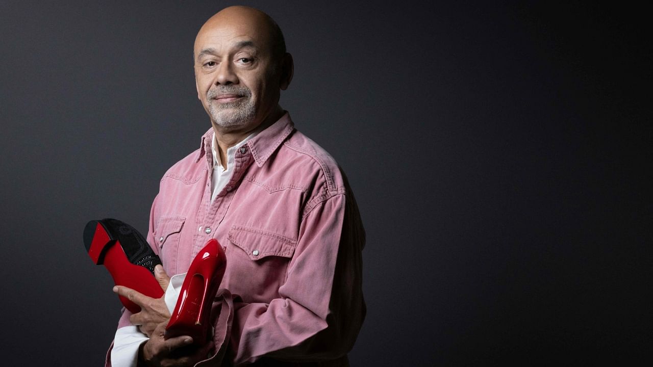 French shoe designer Christian Louboutin poses with two of his creations during a photo session in Paris, on March 2, 2023. Credit: AFP Photo
