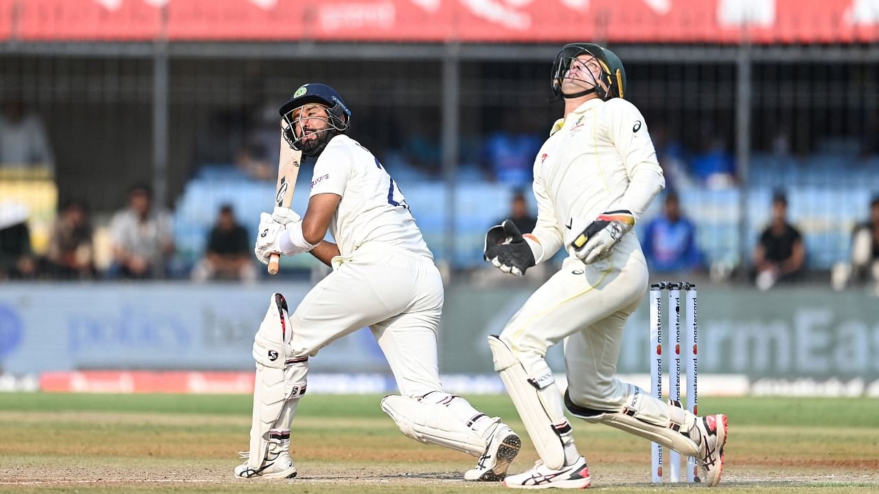India's Cheteshwar Pujara (L) and Australia's Alex Carey (R) eye the ball during the second day of the third Test cricket match between India and Australia at the Holkar Stadium in Indore on March 2. Credit: AFP Photo