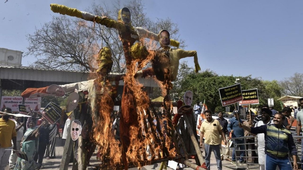 BJP leader Ramvir Singh Bidhuri with party workers burn effigies to protest against Delhi CM Aevind Kejriwal and AAP leader Manish Sisodia over corruption, at Connaught Place in New Delhi. Credit: IANS Photo