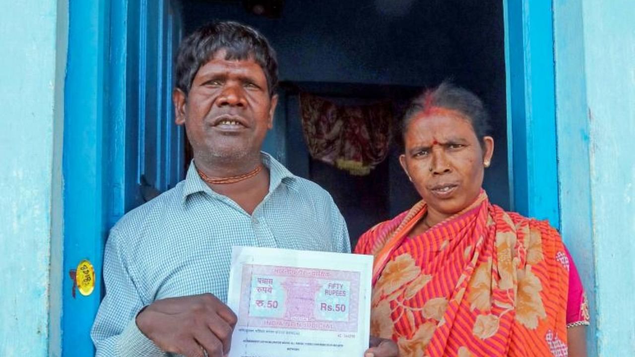 Kacha Badam fame singer Bhuban Badyakar with his wife Aduri shows his agreement paper with a music company, at Dubrajpur in Birbhum district of West Bengal. Credit: PTI Photo