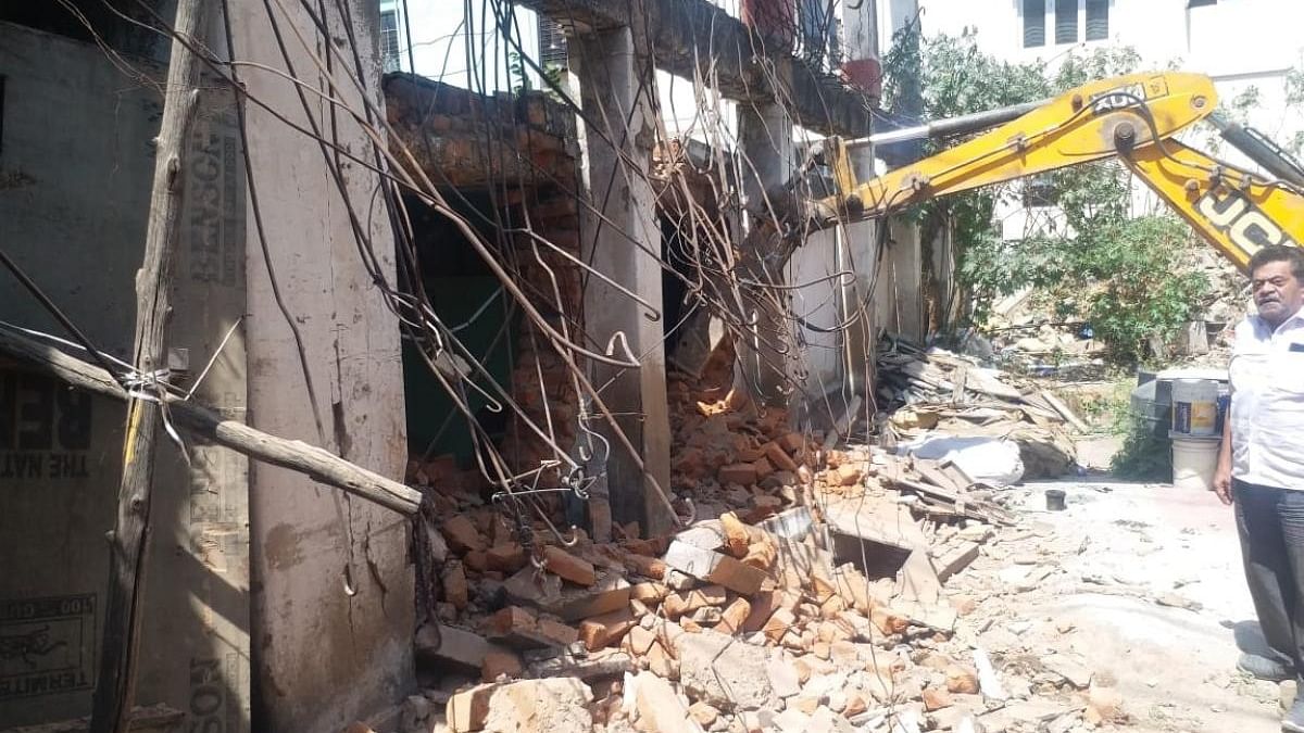 A JCB demolishes a structure at Gandhi Bazaar on Tuesday. DH Photo/Sneha Ramesh