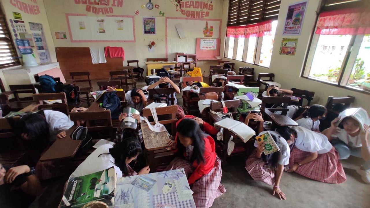 This handout photo taken and received from Buso National High School on March 7, 2023 shows students taking shelter inside their classroom in Mati, after a 6.0-magnitude earthquake jolted the southern Philippines. Credit: AFP PHOTO / Buso National High School