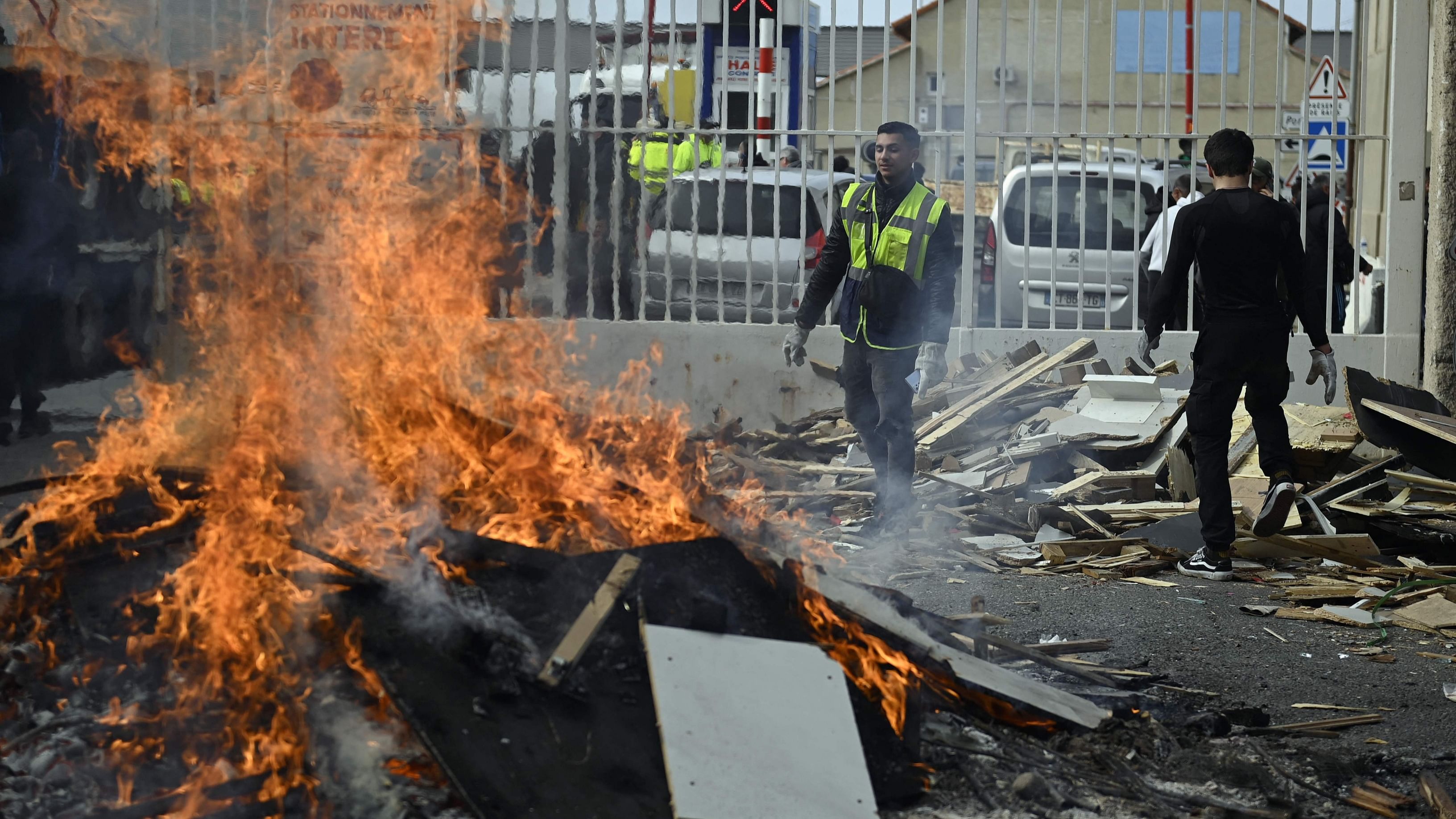 Striking dockers of Marseille's harbour set a fire at one of its entrance during a blockade as part of the movement against the government's proposed pensions reform in Marseille, on March 8, 2023. Credit: AFP Photo