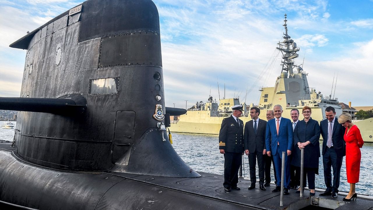 A file photo taken on May 2, 2018 shows French President Emmanuel Macron (2/L) and Australian Prime Minister Malcolm Turnbull (C) standing on the deck of HMAS Waller, a Collins-class submarine operated by the Royal Australian Navy, at Garden Island in Sydney. Australia scrapped a 66 billion USD deal with France, replacing it with nuclear-powered subs using US and British technology. Credit: AFP File Photo