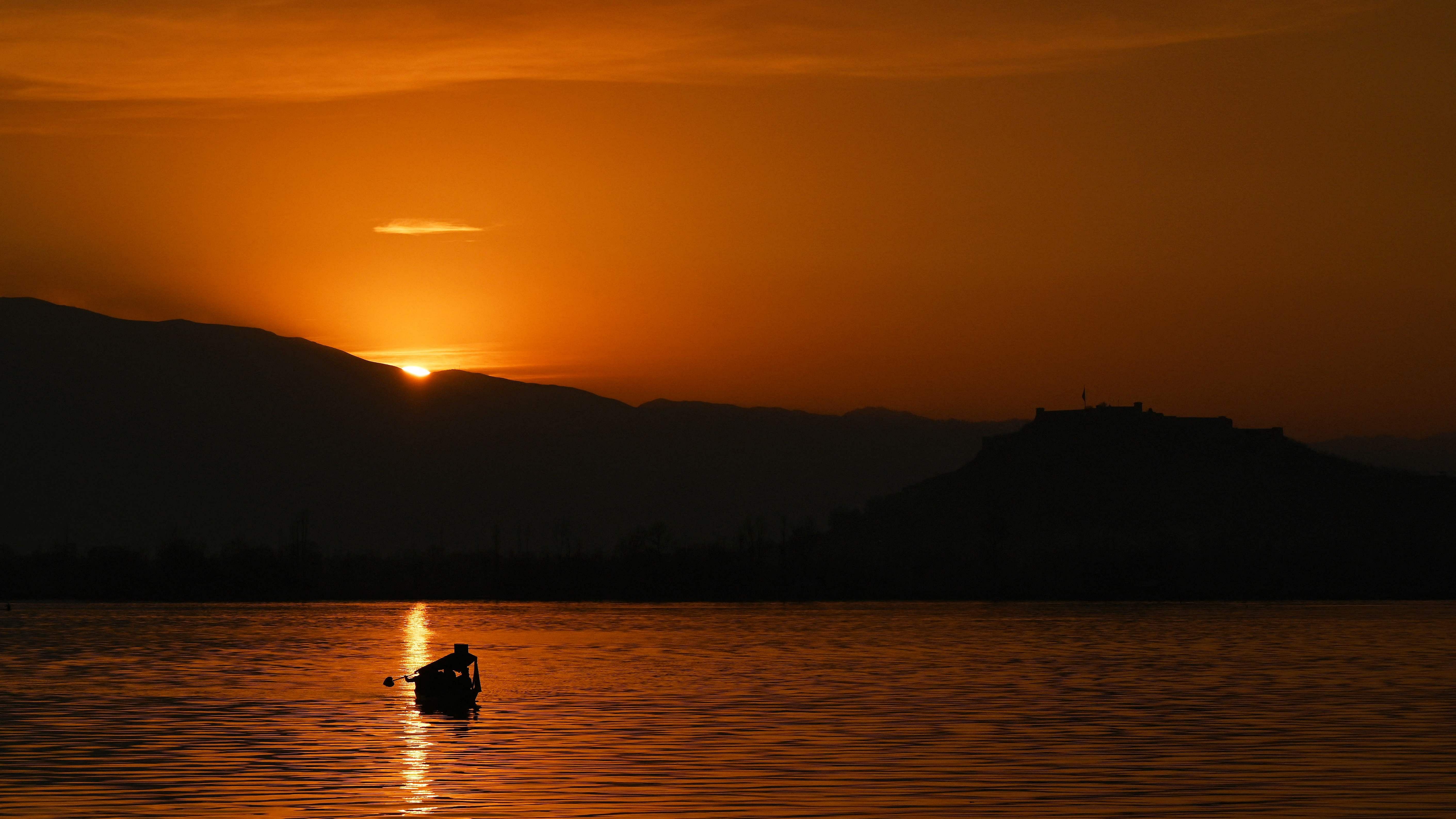 A man steers his boat in Dal Lake during sunset in Srinagar on March 9, 2023. Credit: AFP Photo