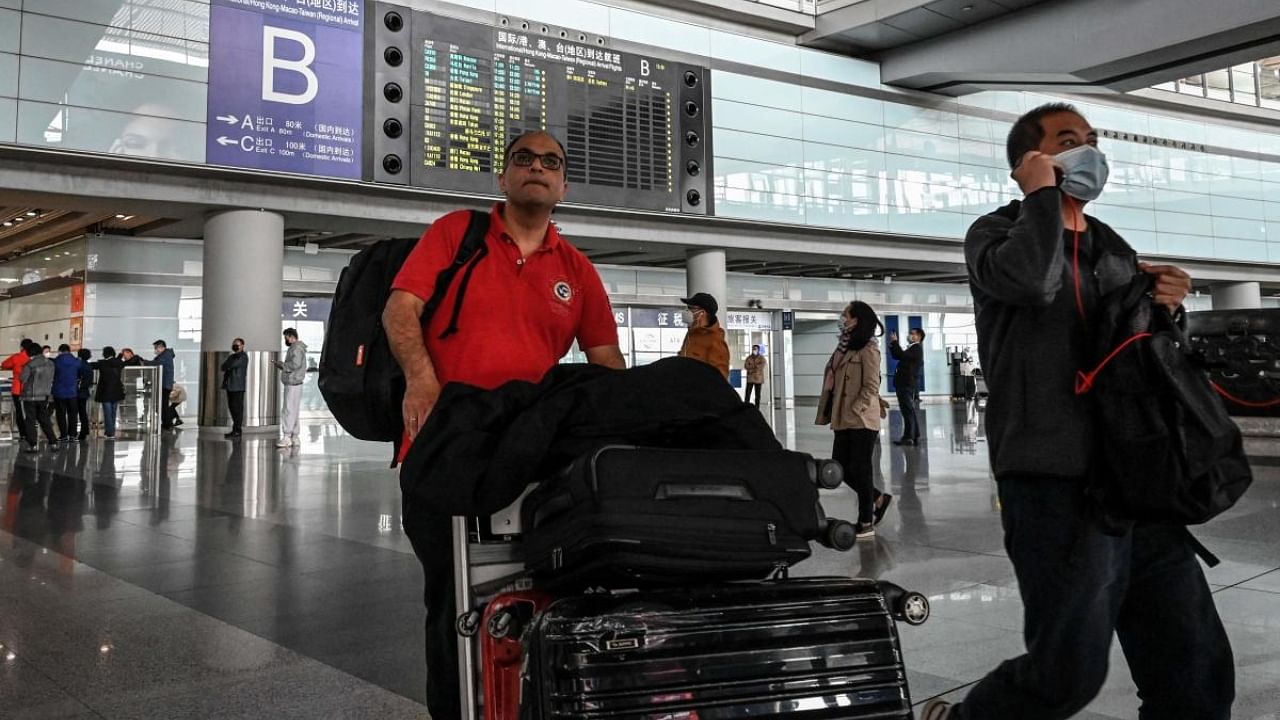 Passengers walk through the arrivals hall for international flights at the Capital International Airport in Beijing on March 14, 2023. Credit: AFP Photo