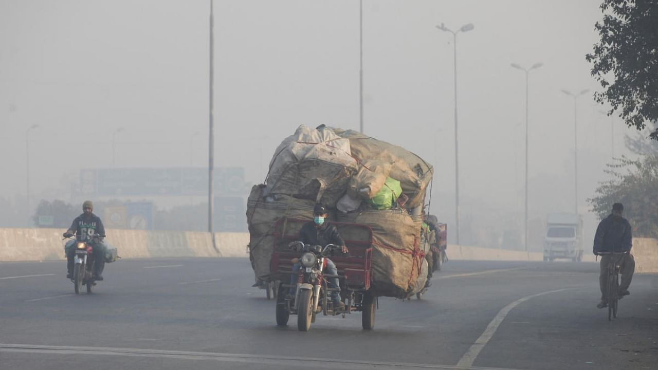 A man rides a motor tricycle, loaded with sacks of recyclables, amid dense smog in Lahore, Pakistan November 24, 2021.  Credit: Reuters File Photo