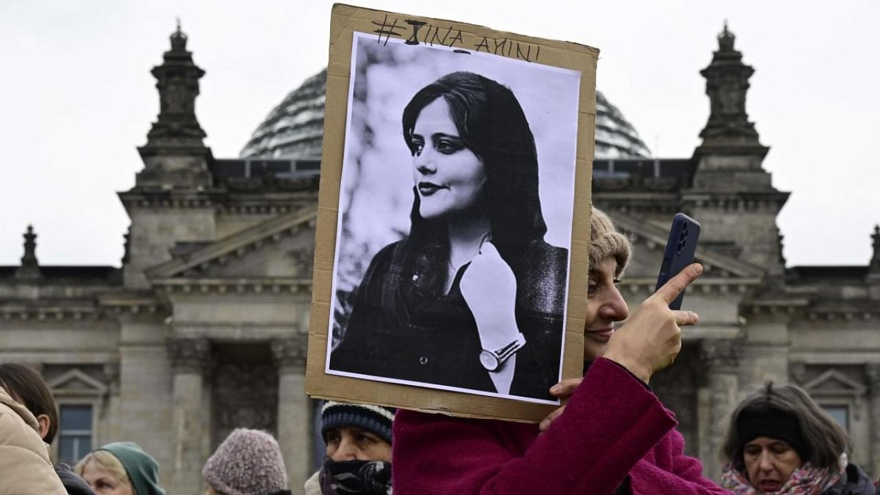A woman takes a selfie as she holds a portrait of Mahsa Amini, a young Iranian woman who died after being arrested in Tehran by the Islamic Republic's morality police, during a demonstration in front of the German lower house of parliament (Bundestag), on the occasion of the International Women's Day, on March 8, 2023. Credit: AFP Photo