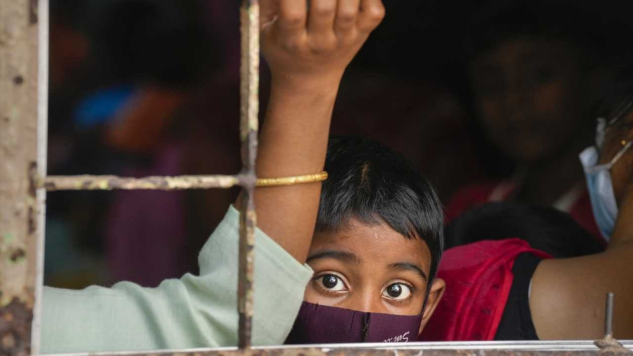 A child wearing a protective face mask looks through a window of Dr B C Roy Post Graduate Institute of Paediatric Sciences in Kolkata. Credit: PTI Photo