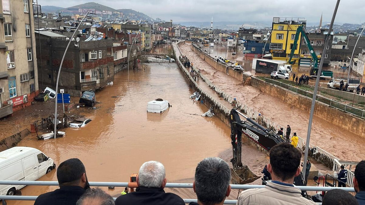 People stand at a high pont looking down at the flood waters in Sanliurfa, southeastern Turkey. Credit: AFP Photo / DHA (Demiroren News Agency)
