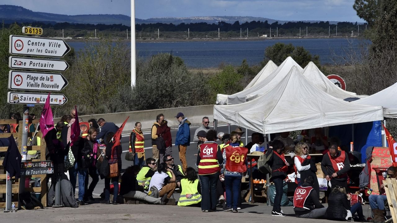 Protesters stand at a barricade as they block access to the petrol storage site of Port-la-Nouvelle, southern France, to protest after the French government pushed a pensions reform through parliament without a vote, using the article 49.3 of the constitution, on March 19, 2023. Credit: AFP Photo
