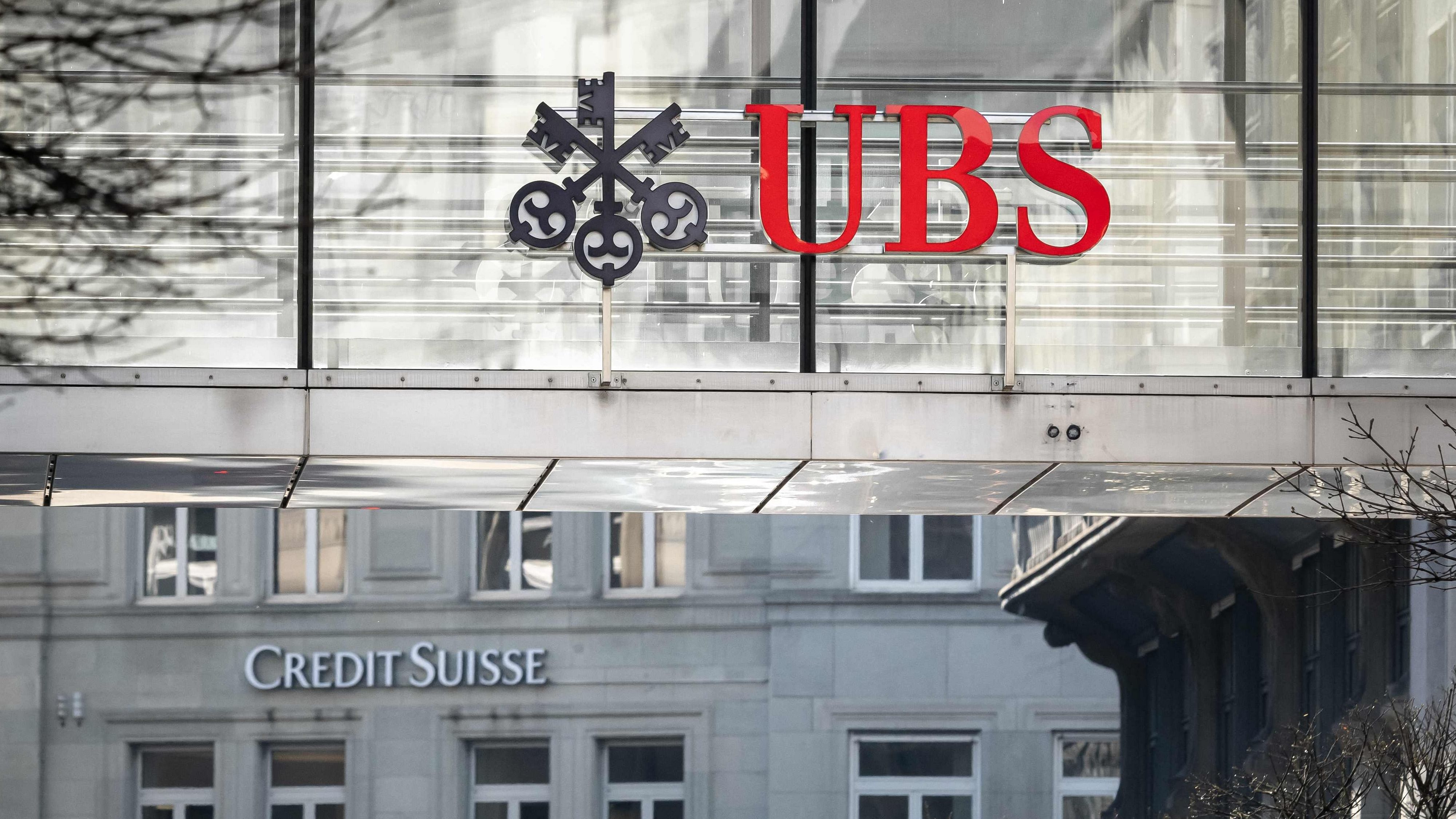 A sign and logo of Credit Suisse bank is seen beneath a sign of Swiss giant banking UBS in Zurich on March 20, 2023. Credit: AFP Photo
