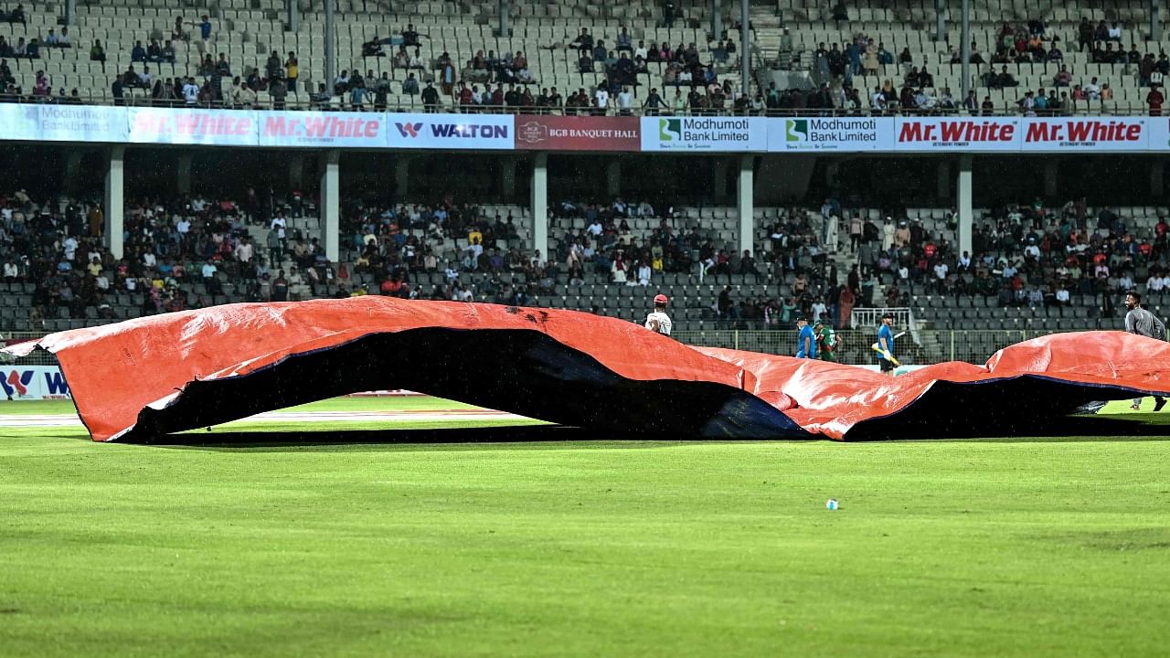 Ground staff cover the pitch with plastic sheets after the match was suspended due to rains during the second one-day international (ODI) cricket match between Bangladesh and Ireland. Credit: AFP Photo