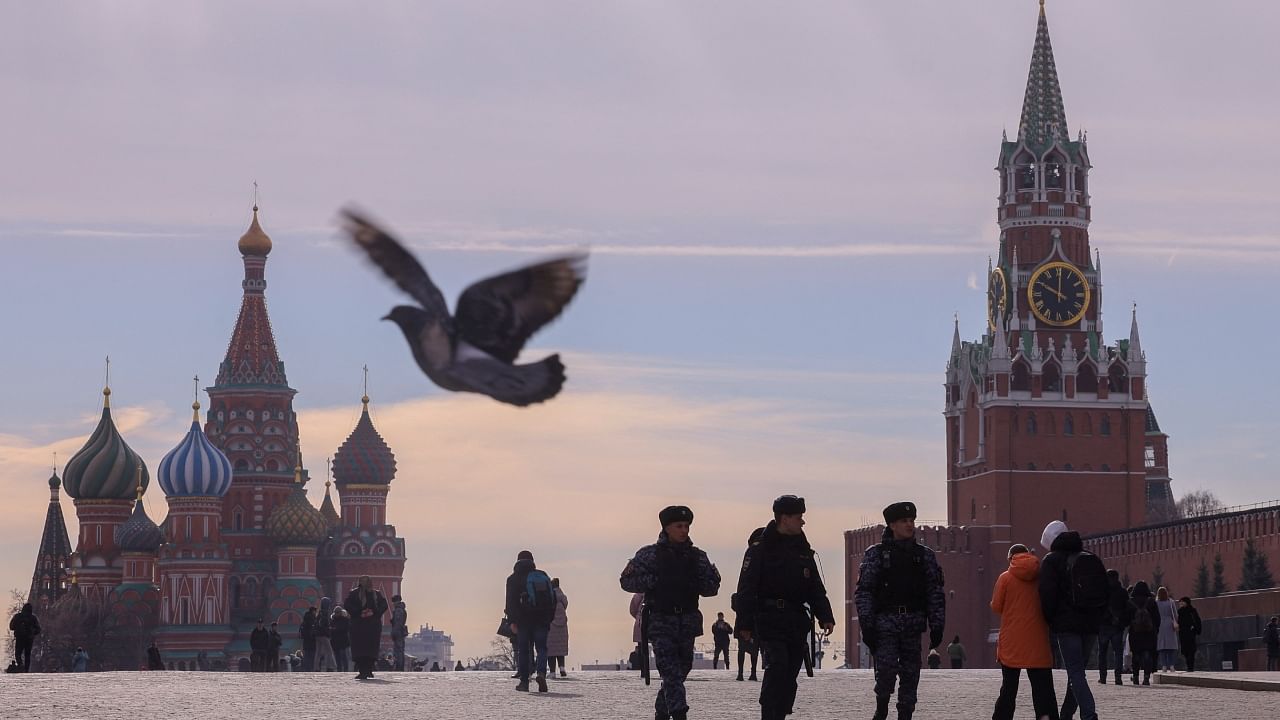 People, including Russian law enforcement officers, walk near St. Basil's Cathedral and the Kremlin's Spasskaya Tower. Credit: Reuters File Photo