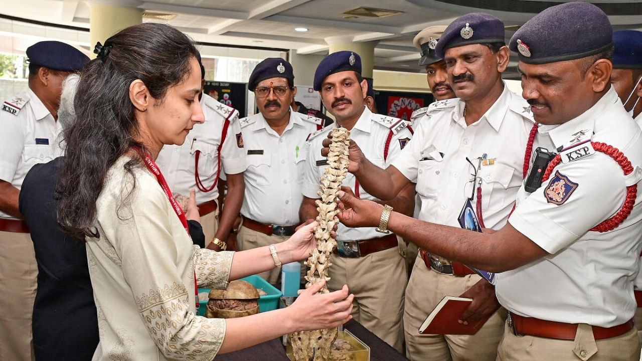 Traffic police officials take a look at anatomy models displayed during the World Head Injury Awareness Day programme at Nimhans in Bengaluru on Monday. Credit: DH Photo
