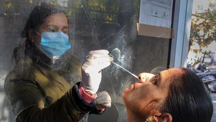 A health worker collects a swab sample from a woman for Covid-19 test. Credit: PTI Photo 