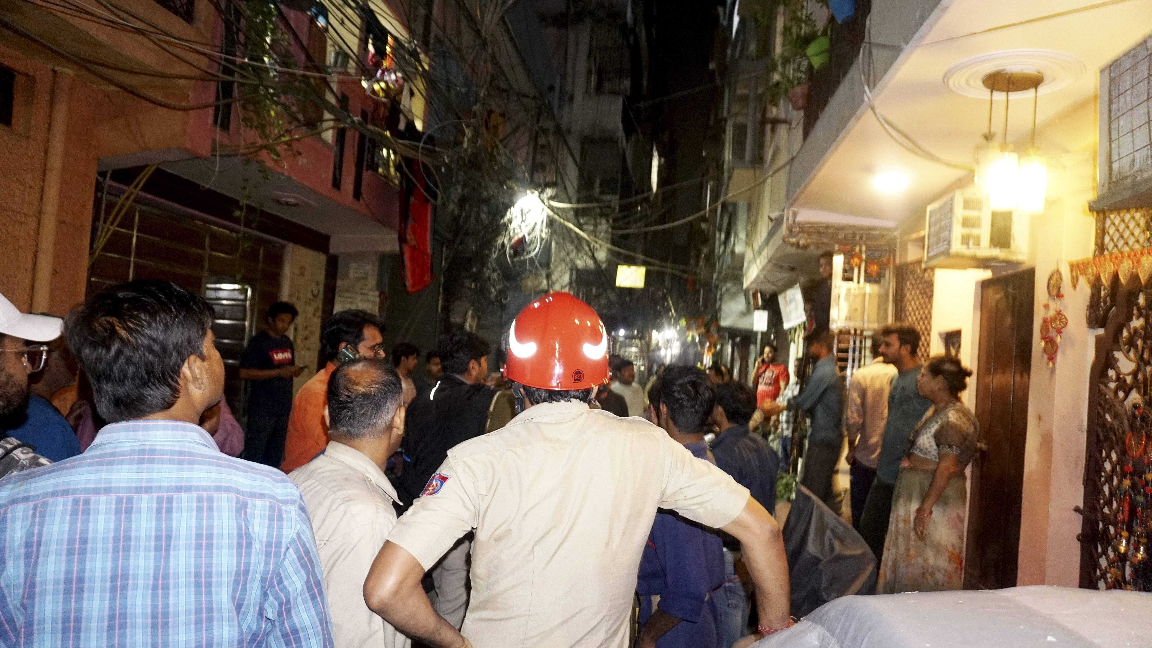 People gather after a building tilts folowing an earthquake, at Shakarpur area in New Delhi. Credit: PTI Photo