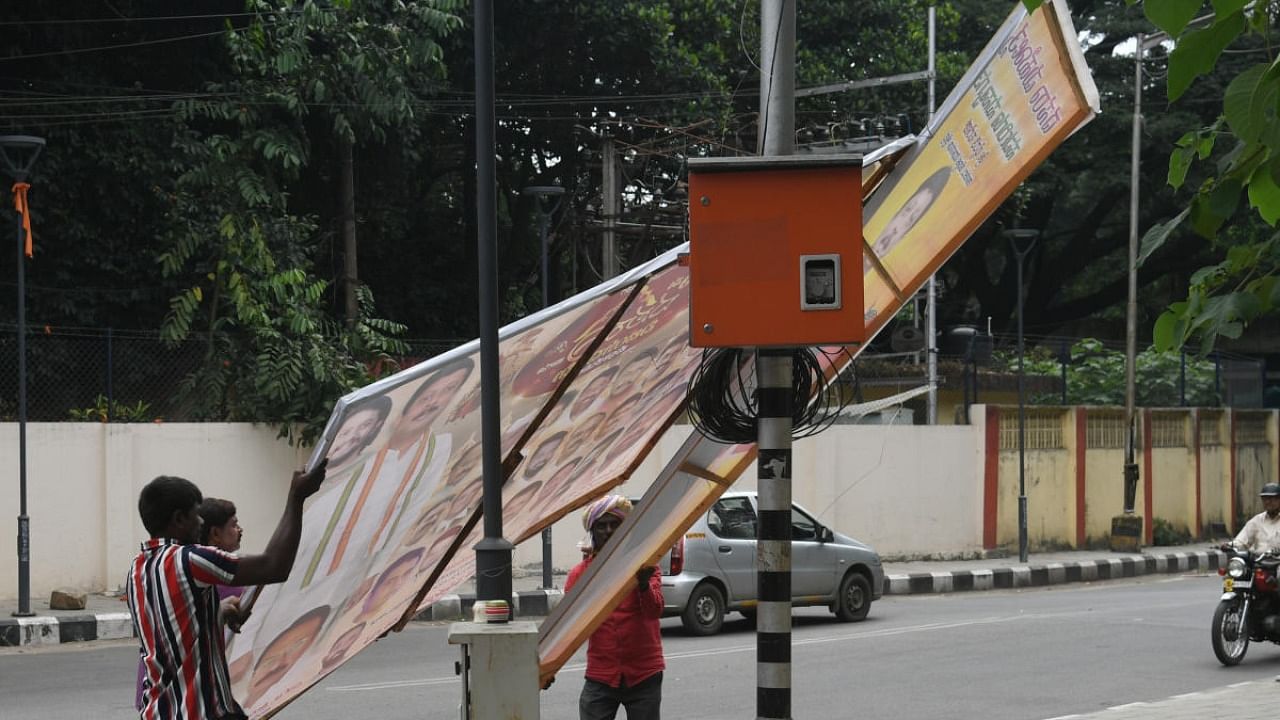 BBMP workers remove flexes installed in the city. DH File Photo / S K Dinesh